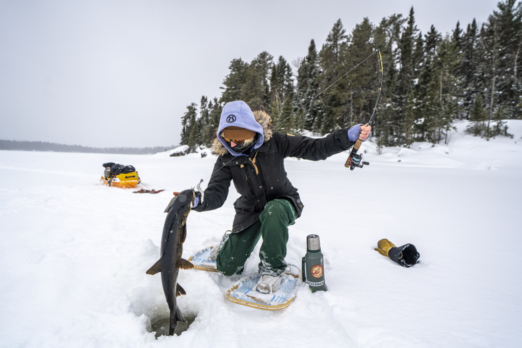 Personne sortant un poisson d’un trou de pêche sur la glace