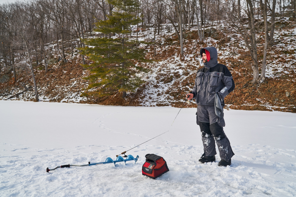 Personne pêchant sur la glace près d’une tarière