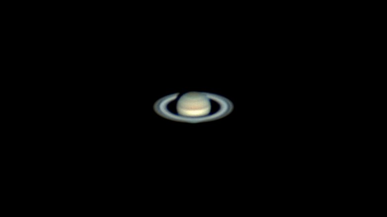 A tiny-looking Saturn in the black of space, its rings clearly visible