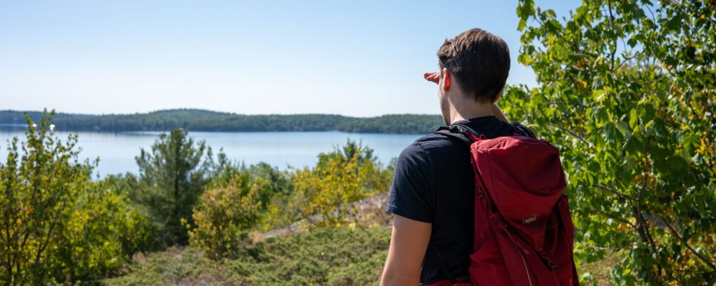 hiker wearing backpack looking out at lake