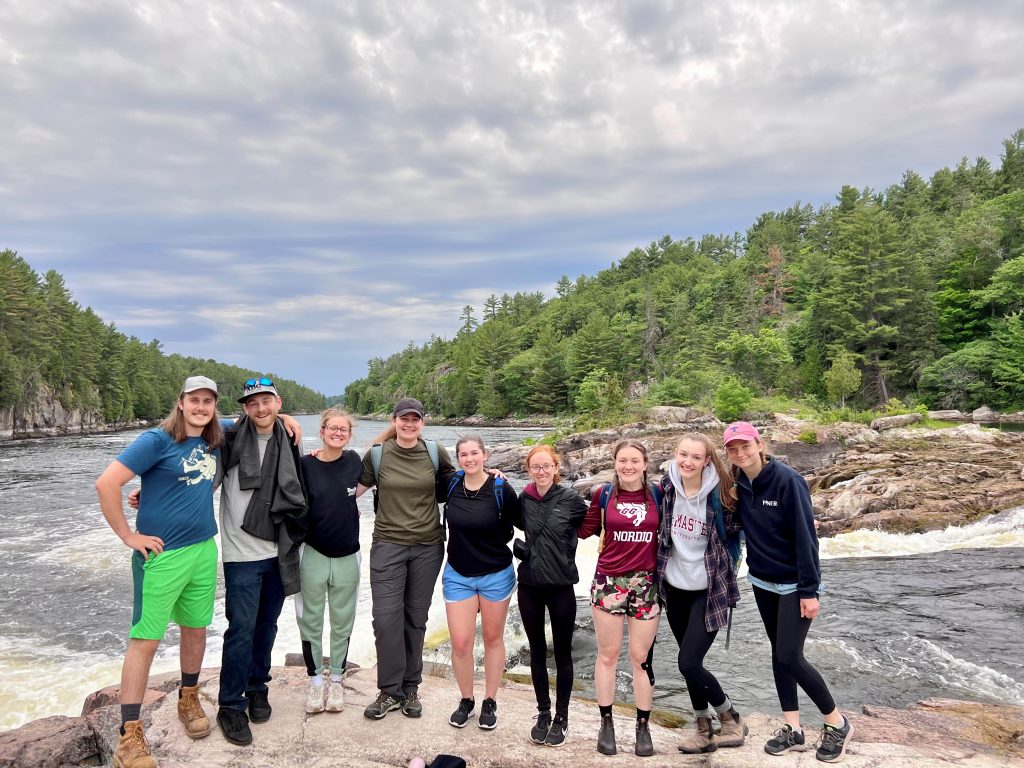 group of staff with arms around each other in front of river
