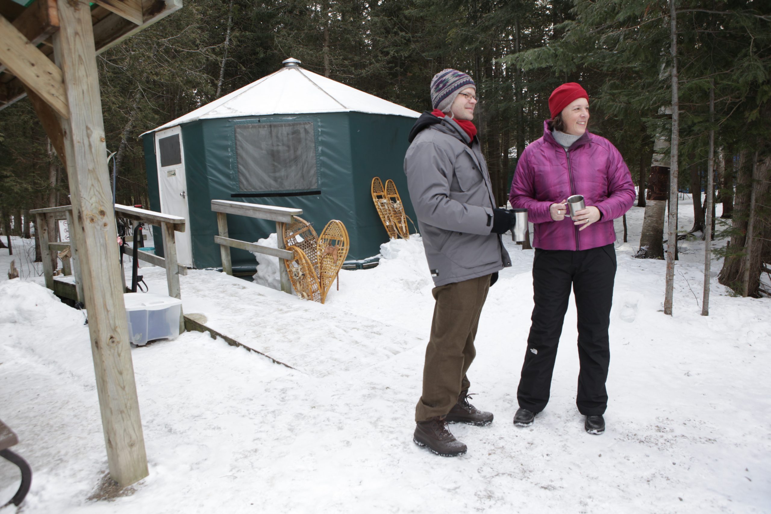 Two people standing in front of yurt with snow on the ground