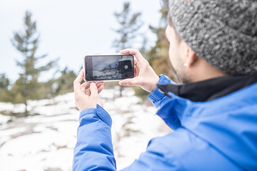 person taking photo of winter landscape using phone