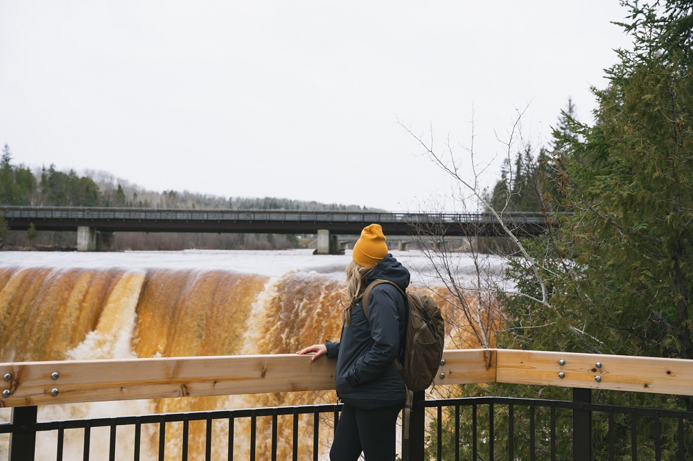 person looking out at waterfall, wearing winter clothing