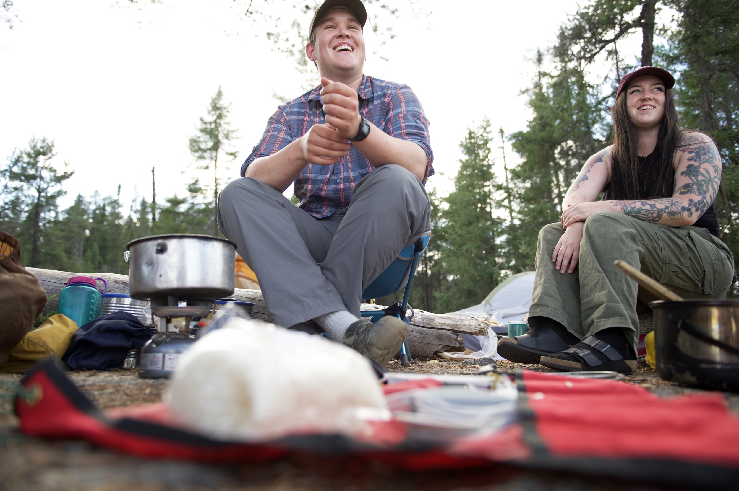 two people sitting on backcountry campsite with dinner prepared in front of them