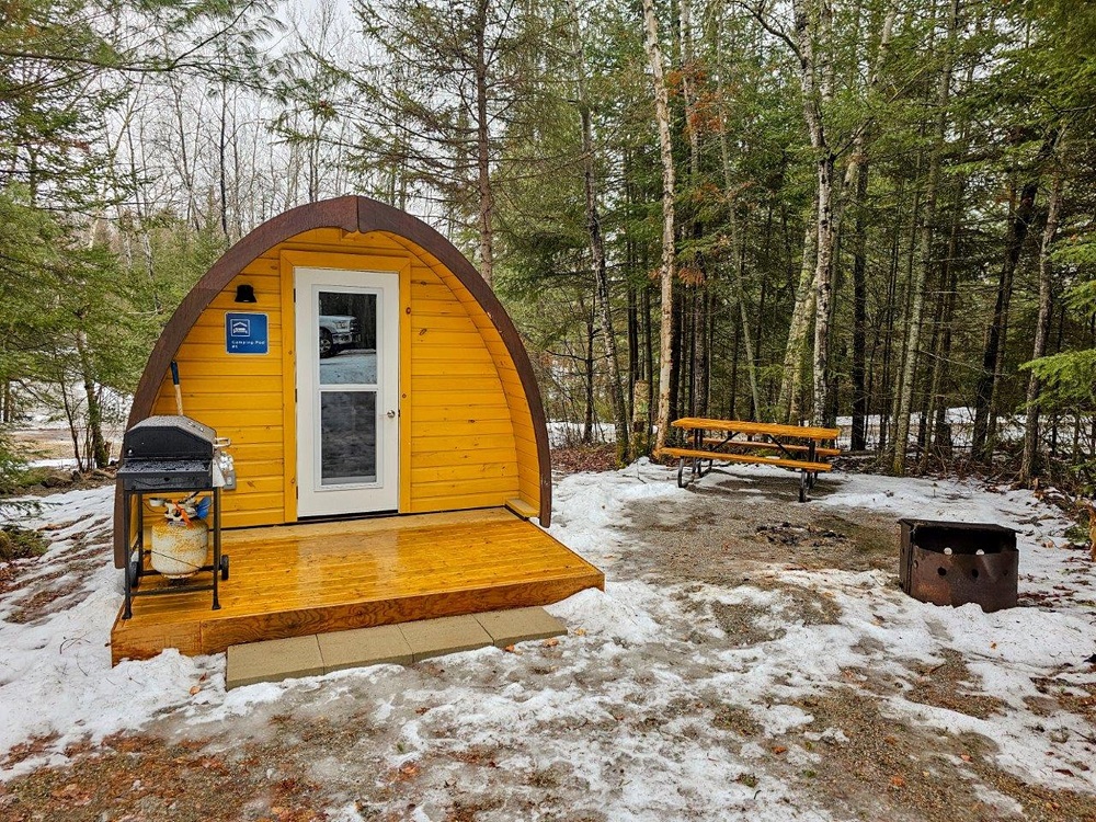 exterior of camping pod with barbecue, picnic table, and fire pit