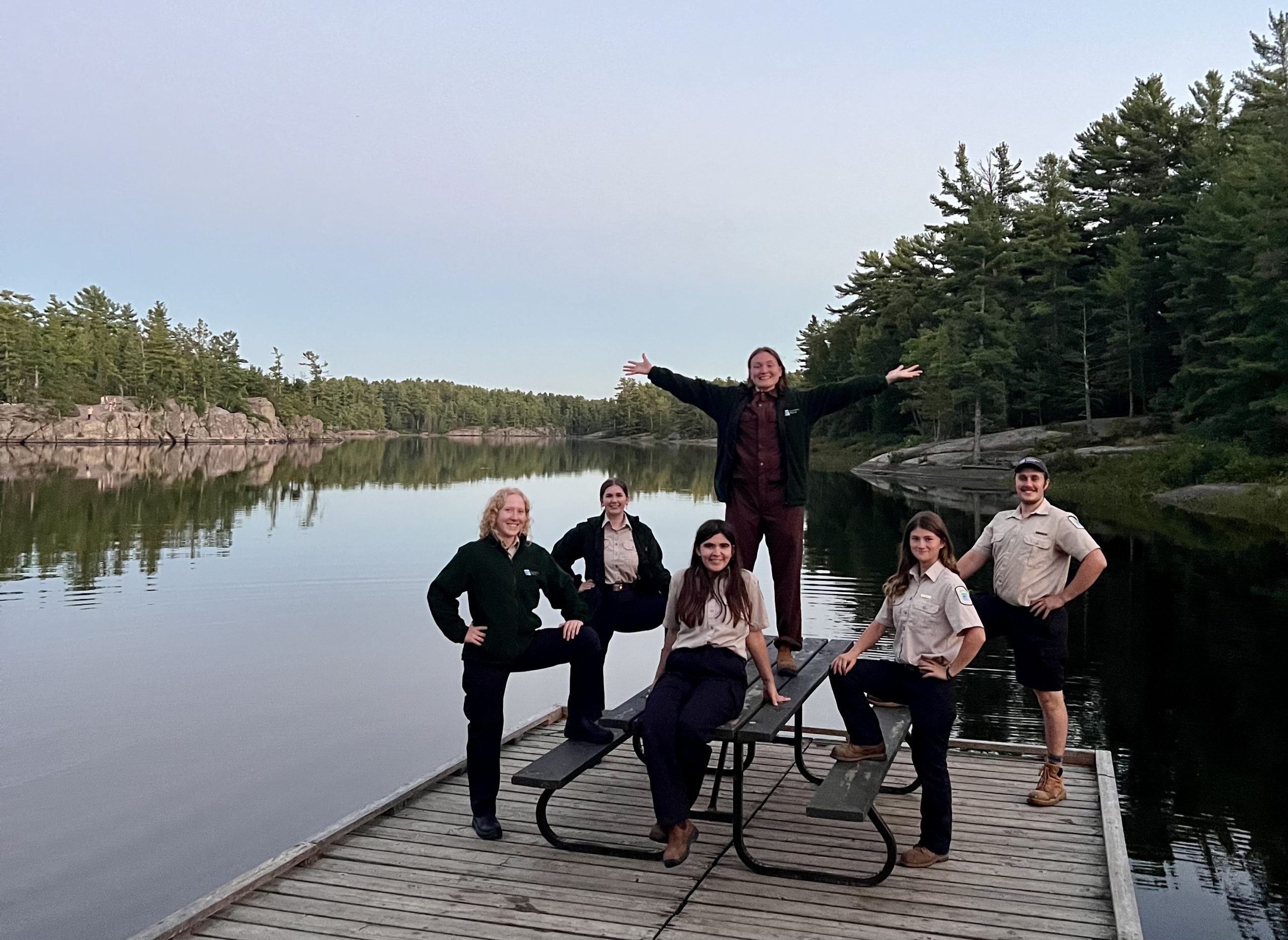 The Grundy Lake Provincial Park Discovery team standing around a picnic table on a dock, with the lake in the background