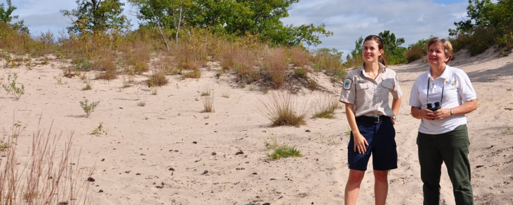 Laurel standing with someone on a sand dune