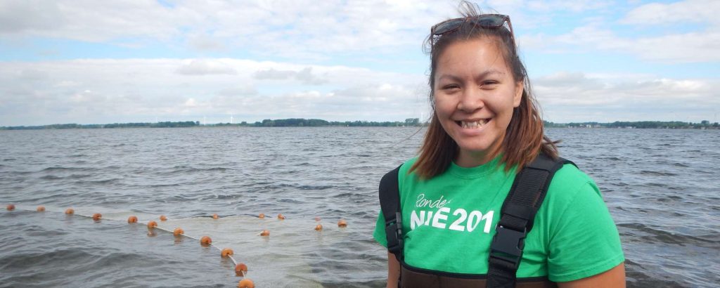 Pilar standing on shore in waders, netting in lake in background