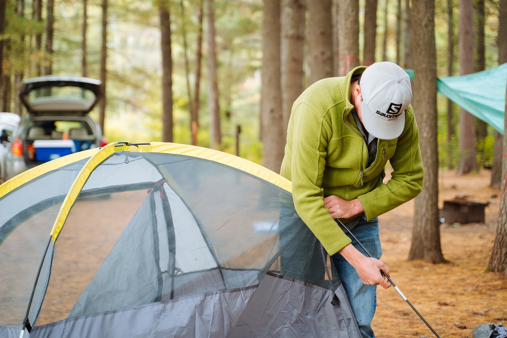 person putting pole through tent