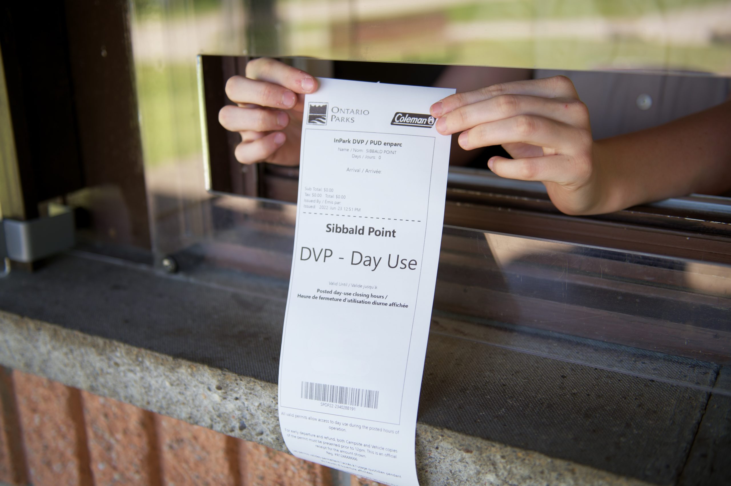 A daily vehicle permit being held out of a service window