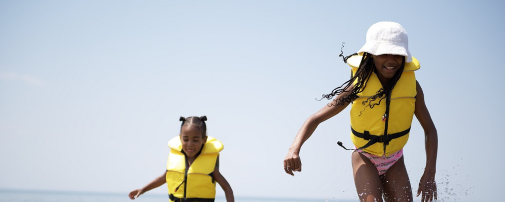 Two kids wearing PFDs playing in the water