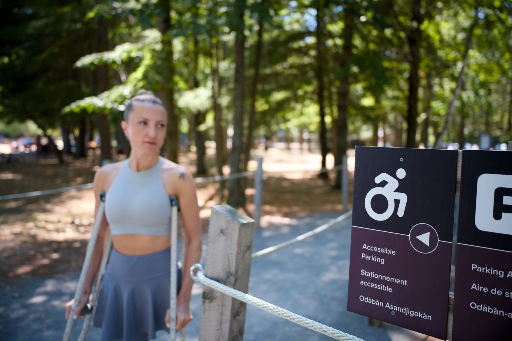 person using crutches beside accessible parking sign 