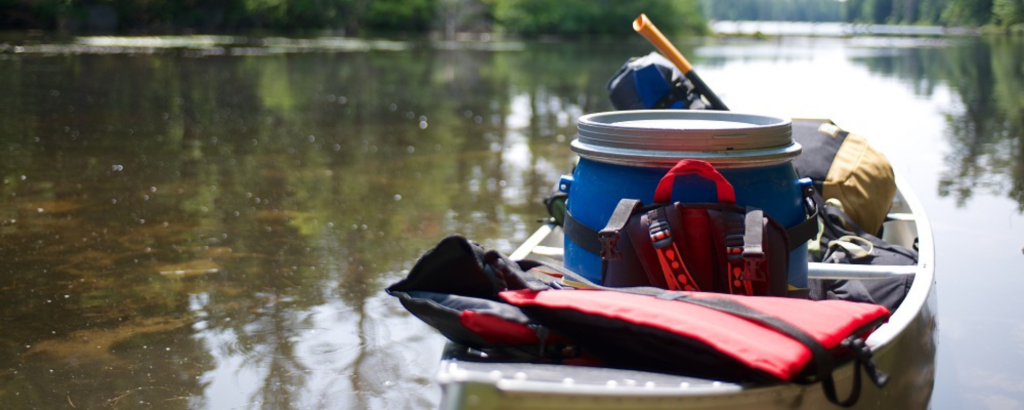 The bow of a canoe loaded with backcountry camping gear, on the water