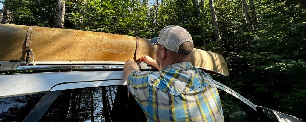 man tying canoe to roof racks