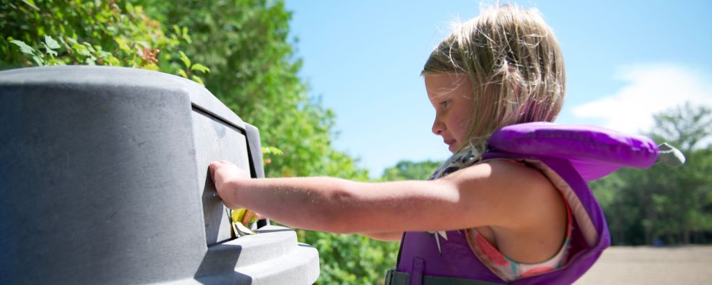 child throwing trash away in receptacle 