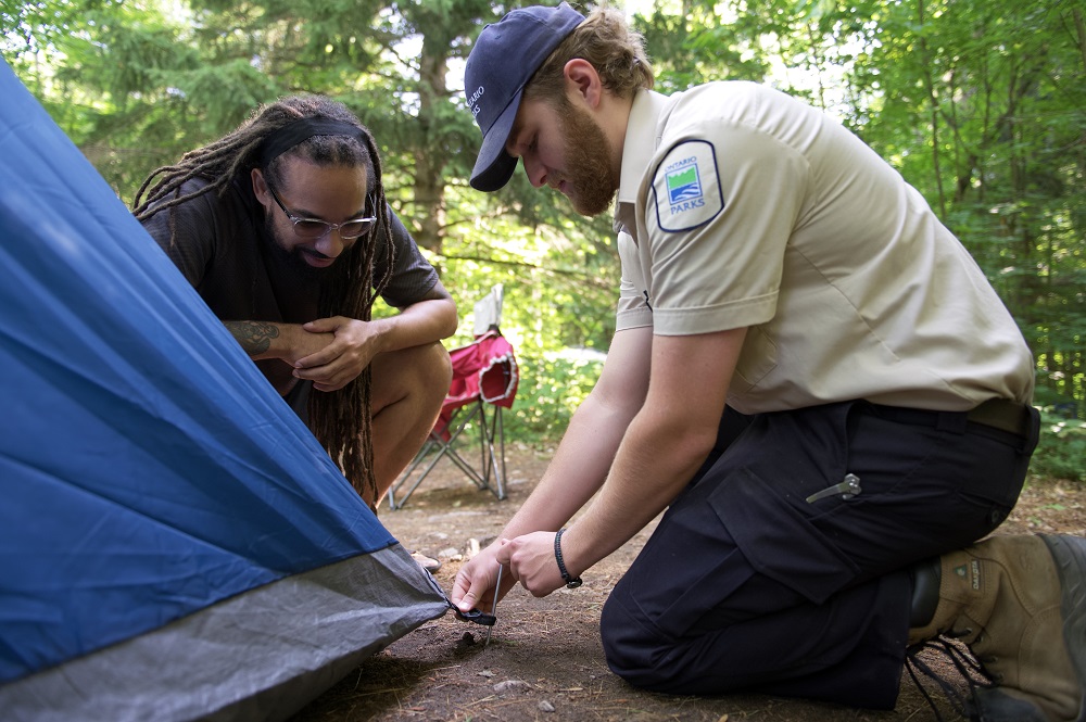 staff helping visitor set up tent