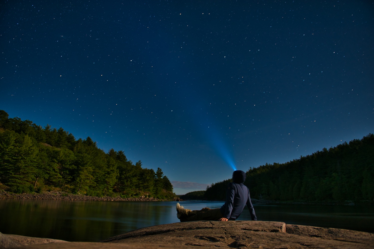 person stargazing sitting on rock