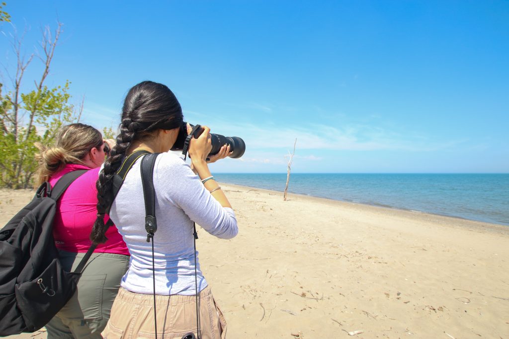 one person taking photo of lake, other looking through binoculars