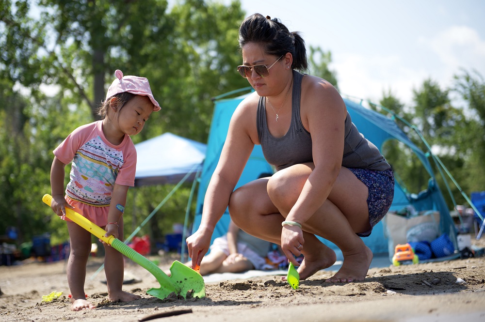 child and mother playing with sand toys on beach