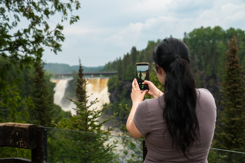 person taking photo of waterfalls from viewing platform