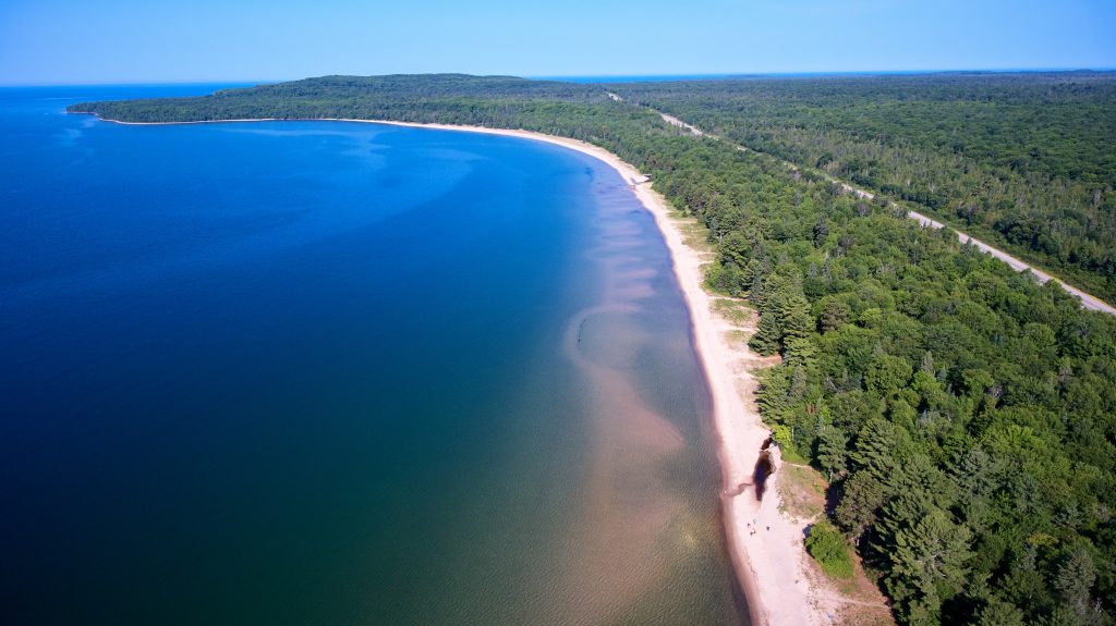aerial view of long, sandy beach along blue lake