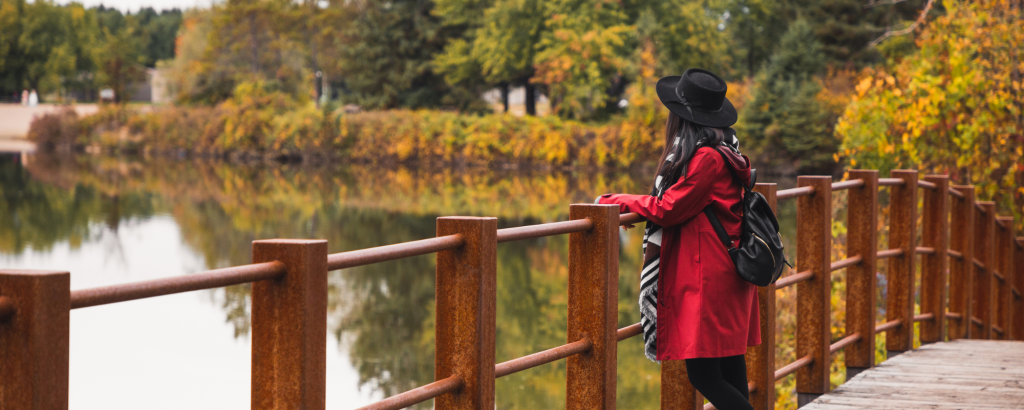 A woman looks out over a bridge onto the water.