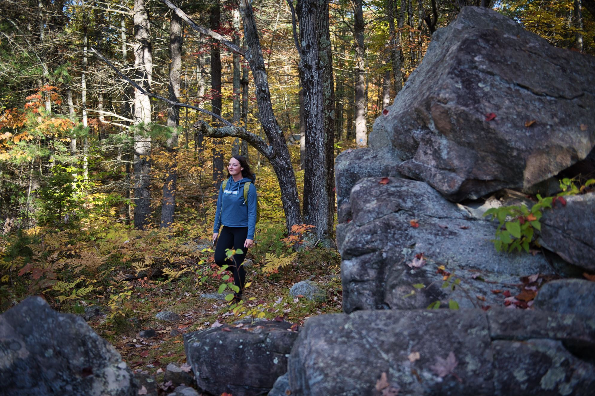 person hiking through forest with large geological formation