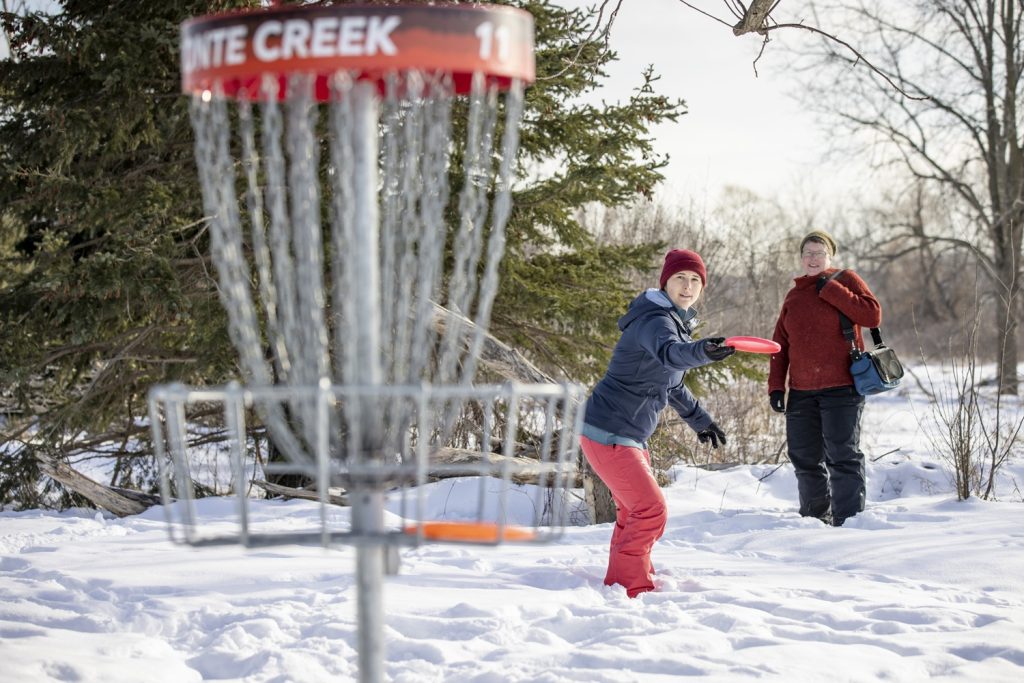 two visitors playing disc golf on snowy course