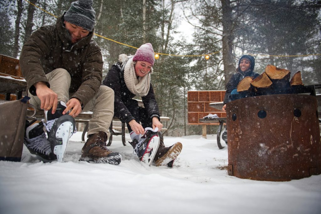 two visitors lacing up skates by the firepit