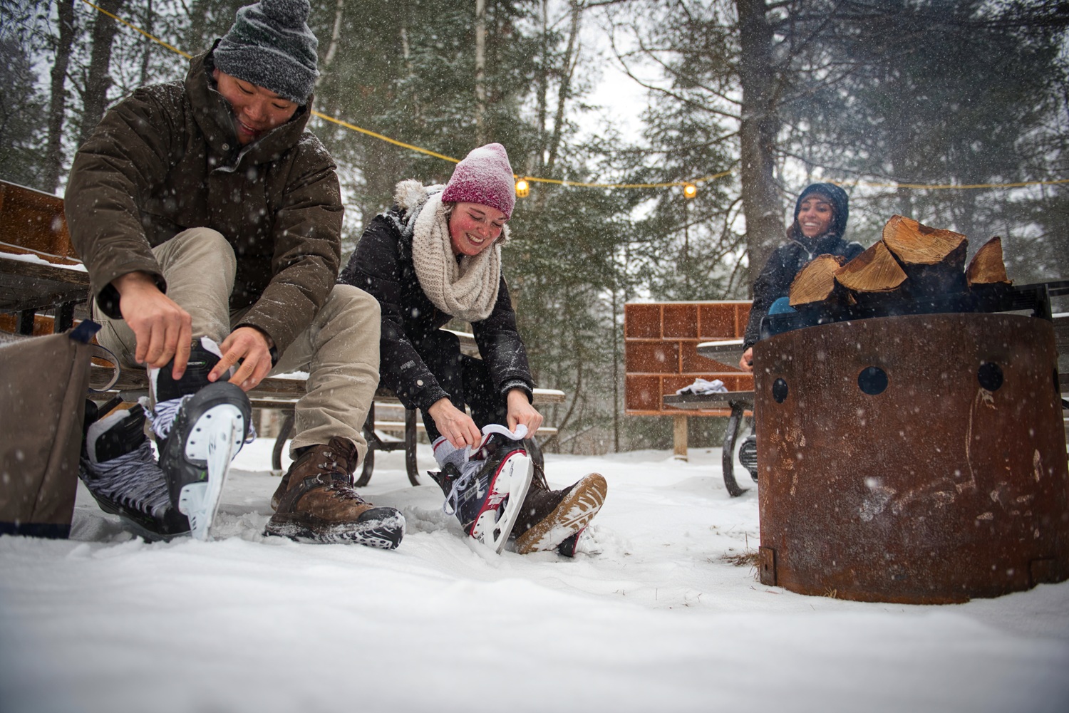 two visitors lacing up skates by the firepit