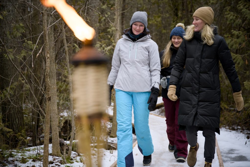 Un groupe de randonneurs sur un sentier éclairé aux flambeaux en hiver