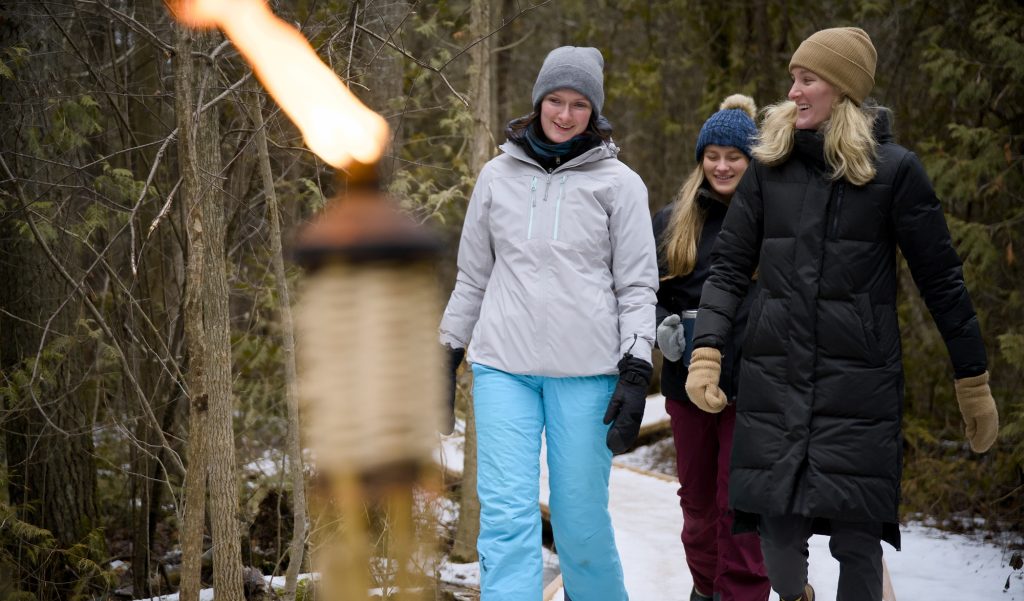 A group of hikers on a torch-lit trail in winter