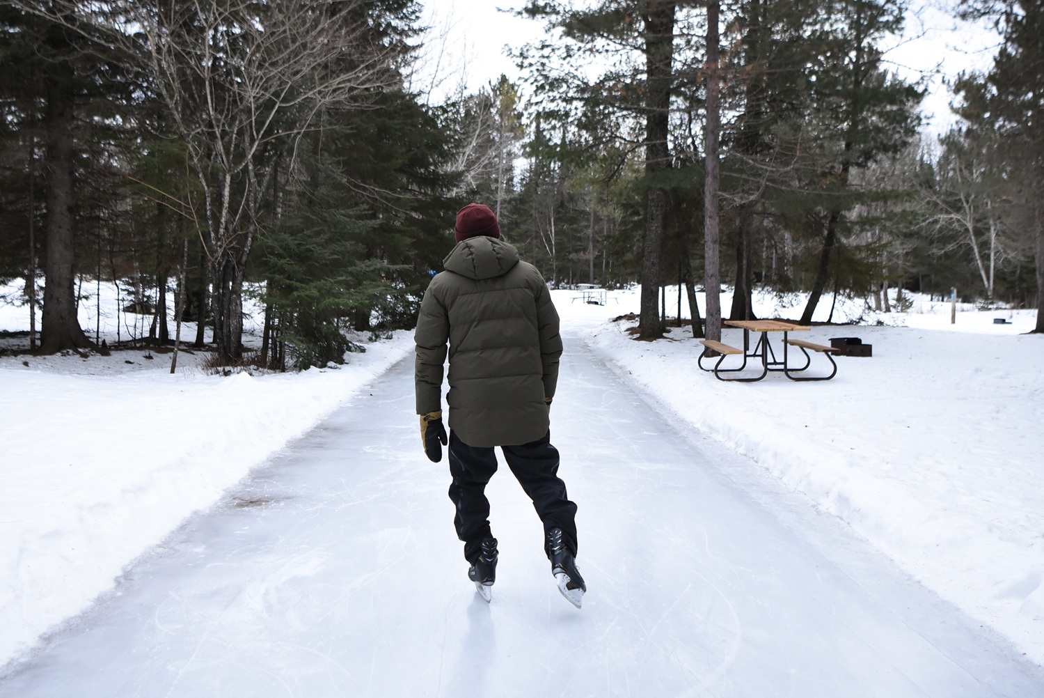 man skating on ice trail through forest