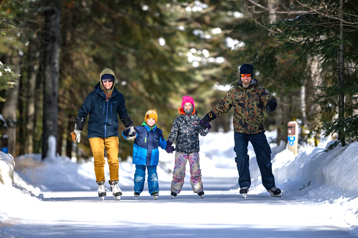 family skating down an ice trail in a winter forest