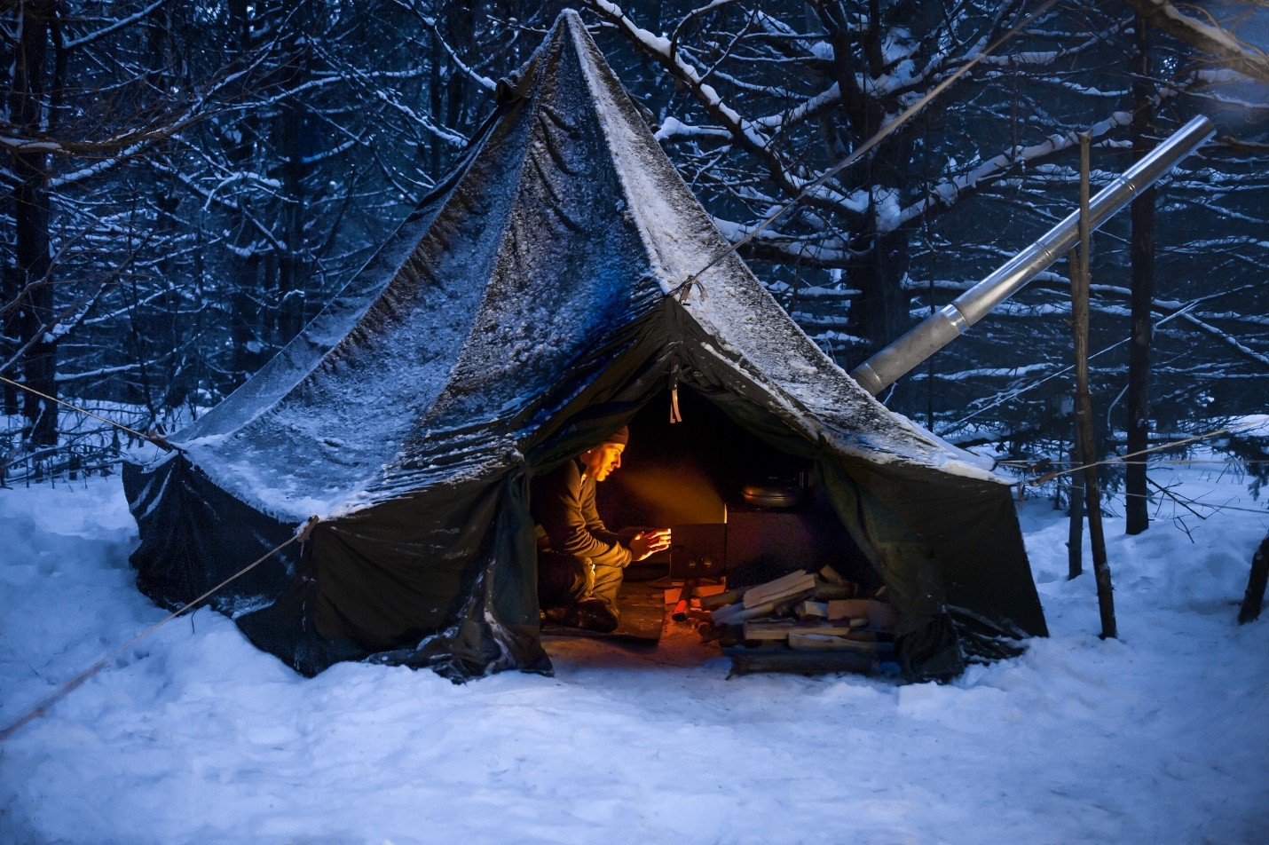 man in a hot tent in a winter forest