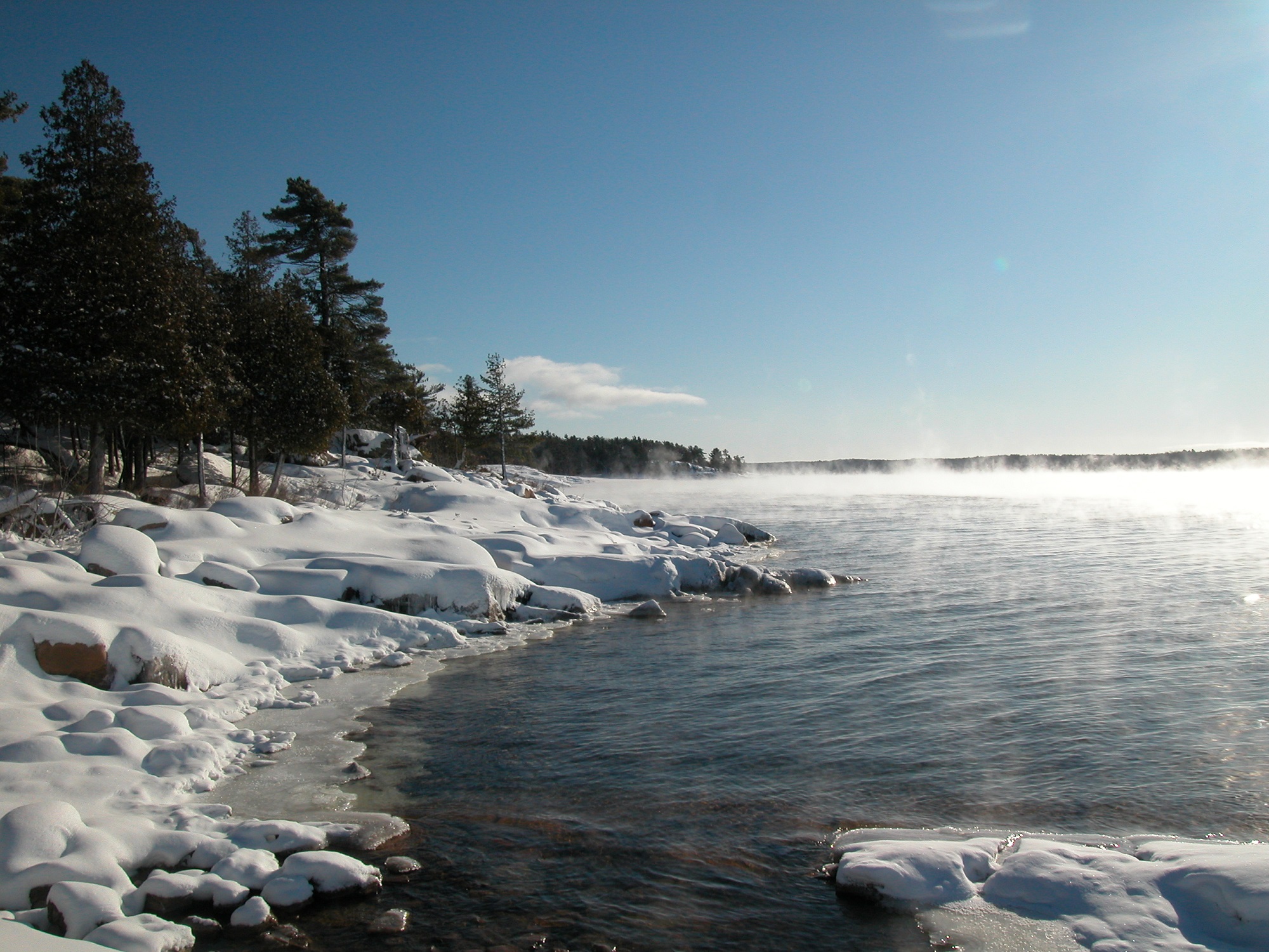 view of partially frozen lake with snowy shore