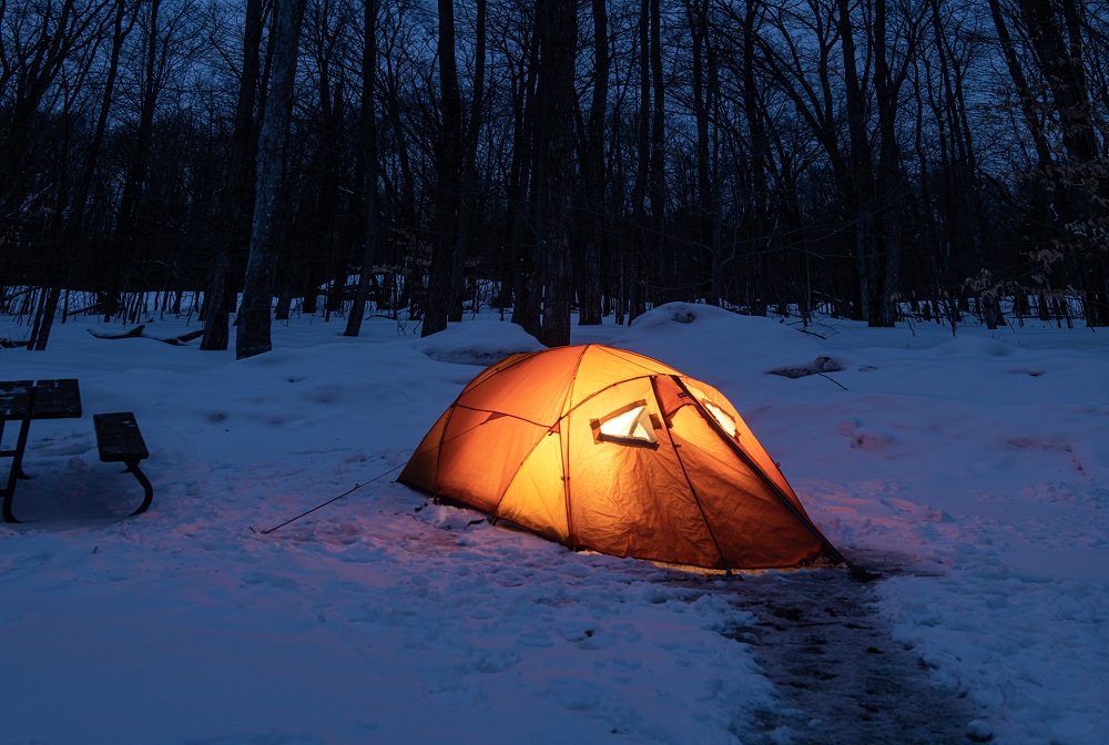 lit tent on snowy campsite at night