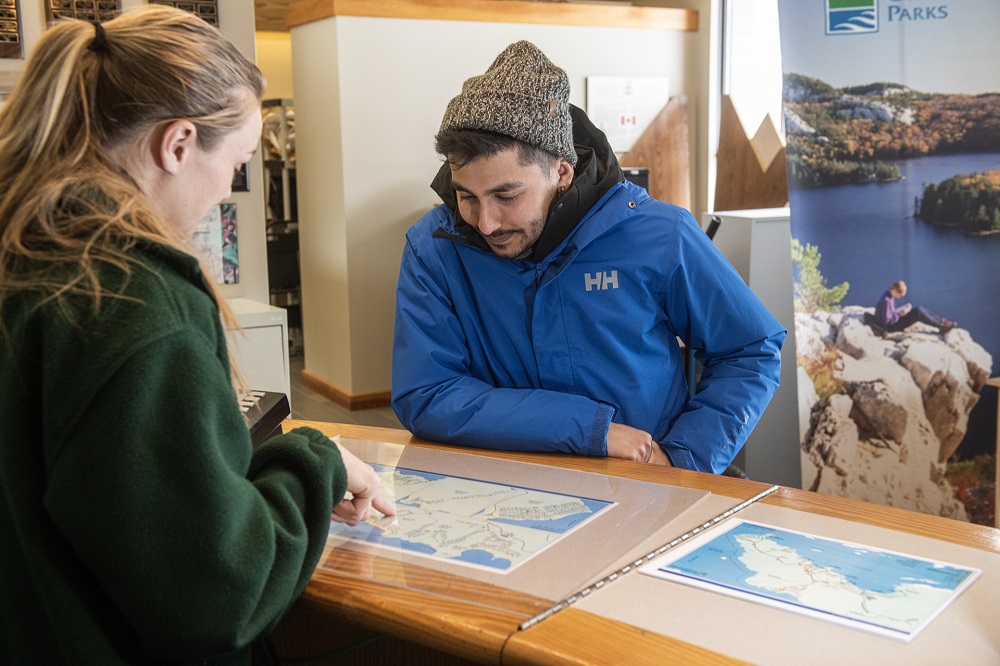 staff pointing to map with visitor in park office