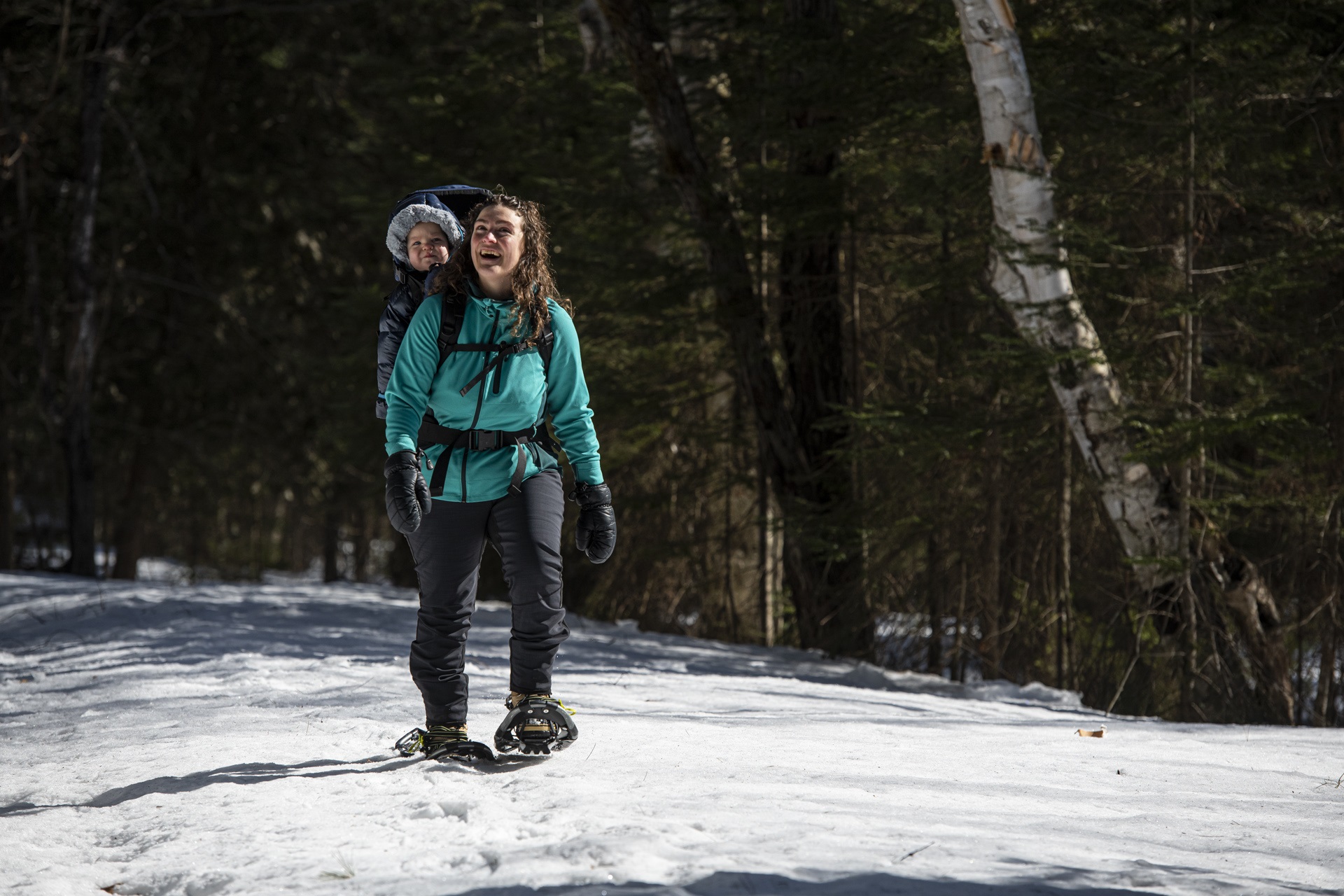 mother snowshoeing with child on back