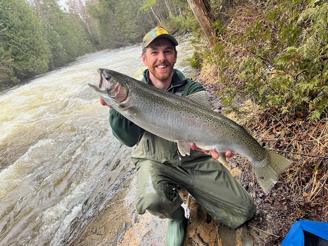 Man holding a Rainbow Trout at side of river