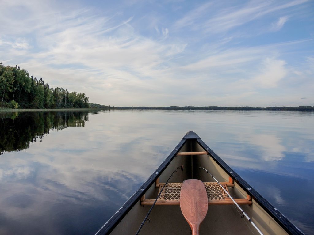 canoe with fishing rods on still lake