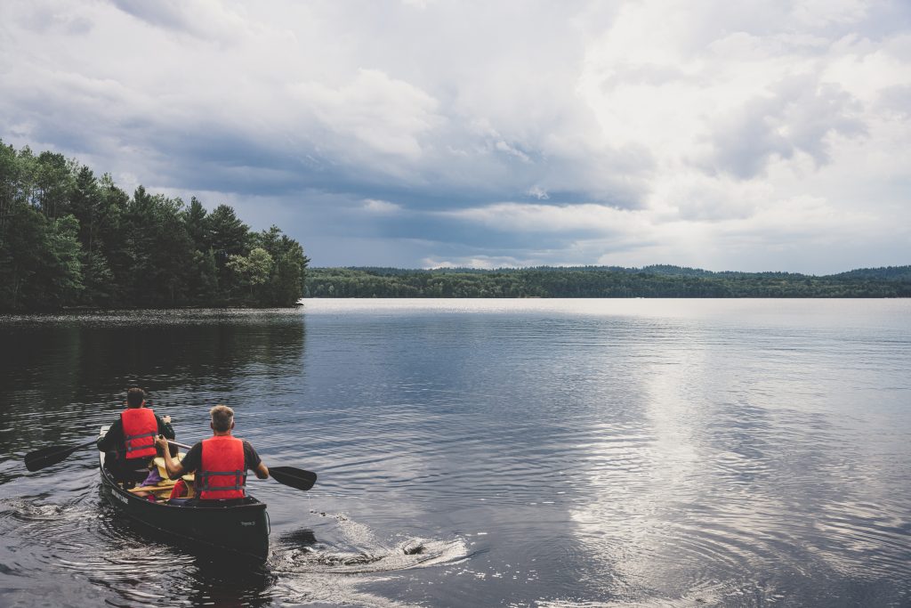 family wearing PFDs, paddling in canoe on lake