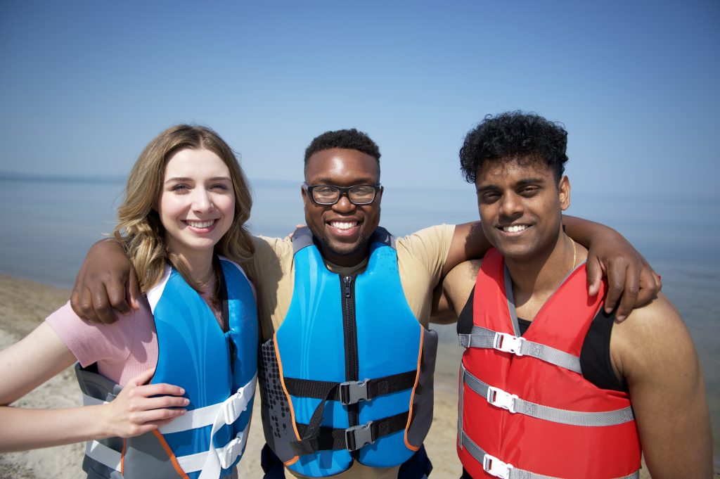 three friends wearing lifejackets on beach
