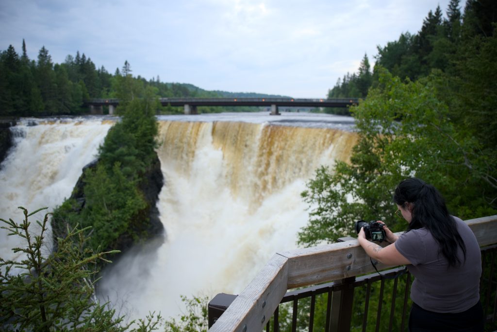 Person taking photo of Kakabeka Falls from viewing pod with DSLR camera