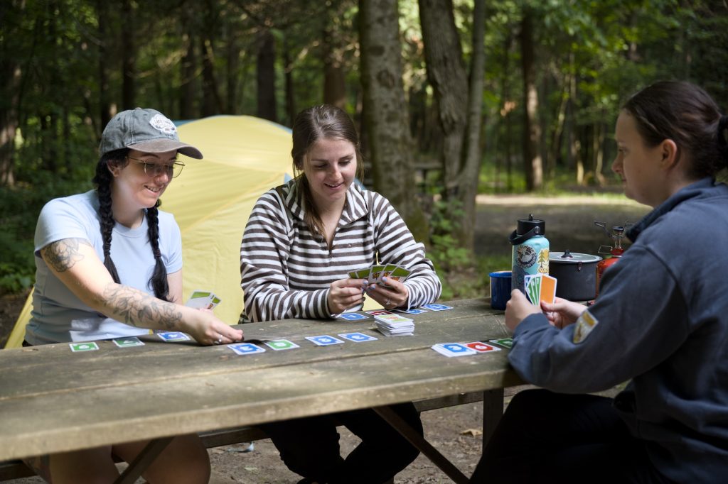 group of campers playing cards at picnic table