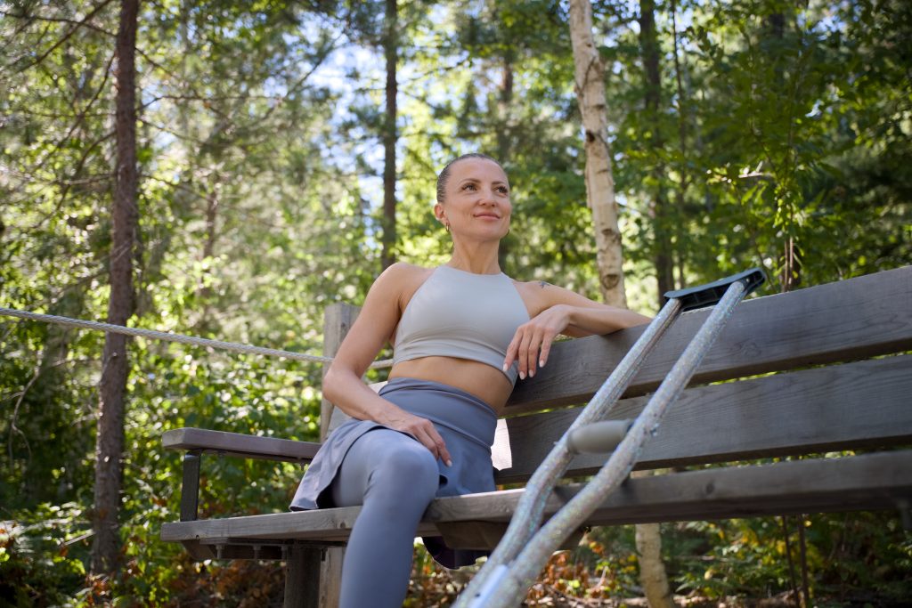 woman with mobility aid sitting on bench in forest