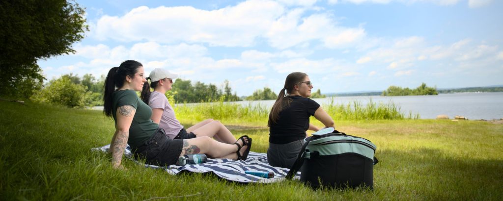 group sitting on grass looking out at lake
