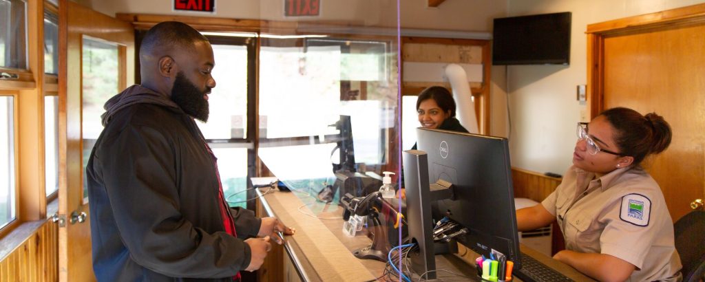 man standing at park desk, park staff standing on other side