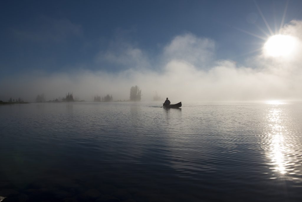 silhouette of person in canoe on lake